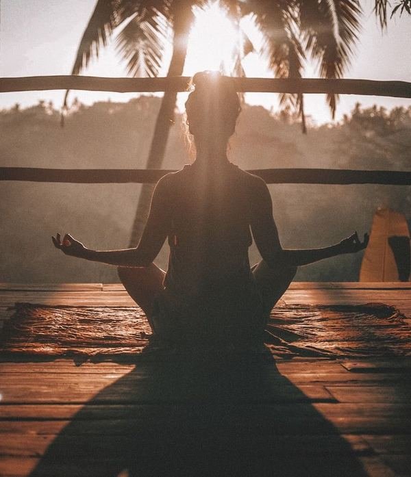 Person seated cross-legged in a calming wellness pose outdoors