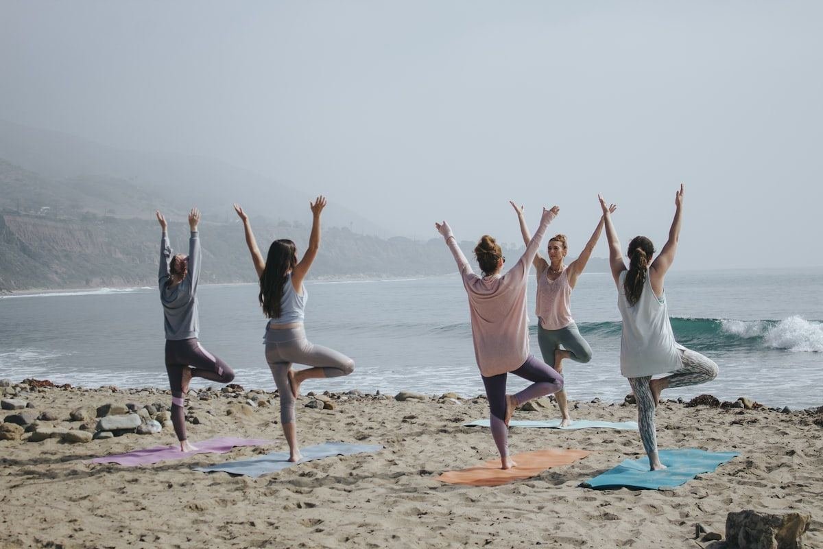 Group practising yoga on the beach at sunrise, representing Ayurvedic wellness